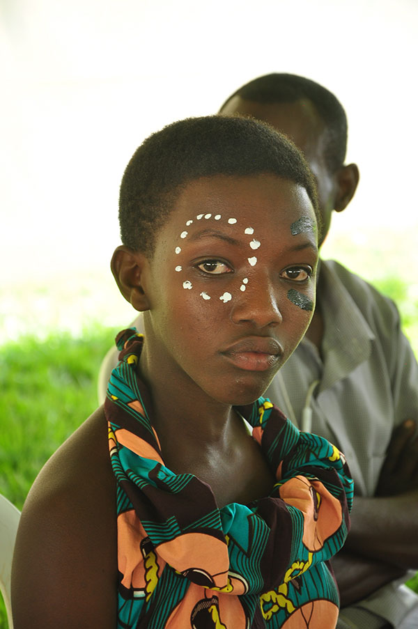 One woman looking at the camera where dots are made around the right eye with paint